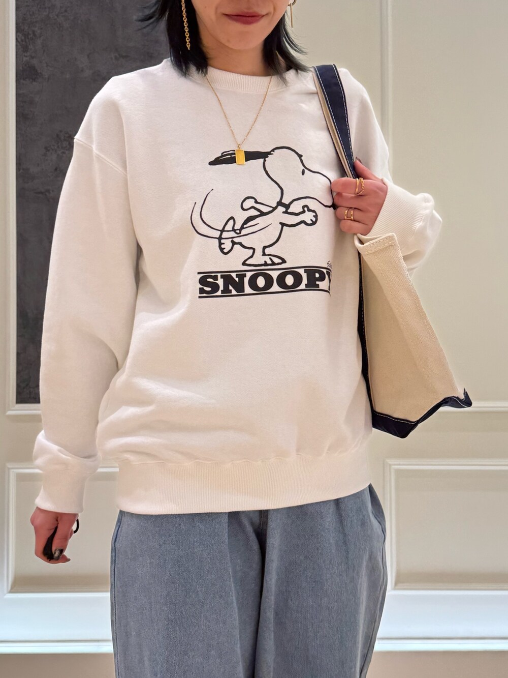 ブルー系のトートバッグ、ホワイト系のスウェット、ブルー系のデニムパンツを着用したレディースの春コーディネートの3枚目の写真