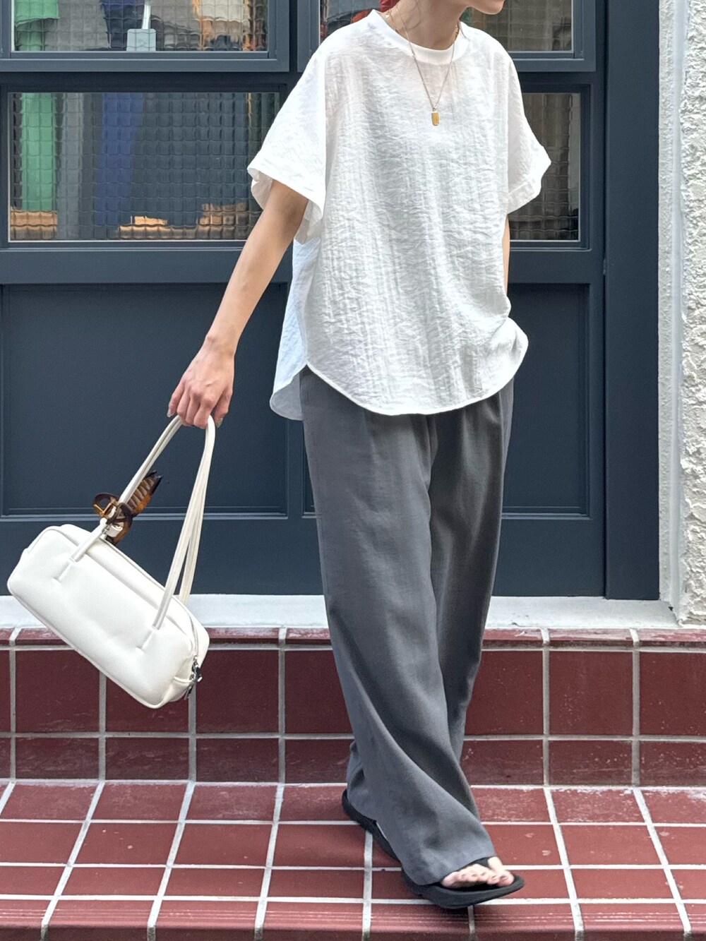 ホワイト系のシャツ/ブラウス、グレー系のサンダル、グレー系のスラックスを着用したレディースの夏コーディネートの2枚目の写真