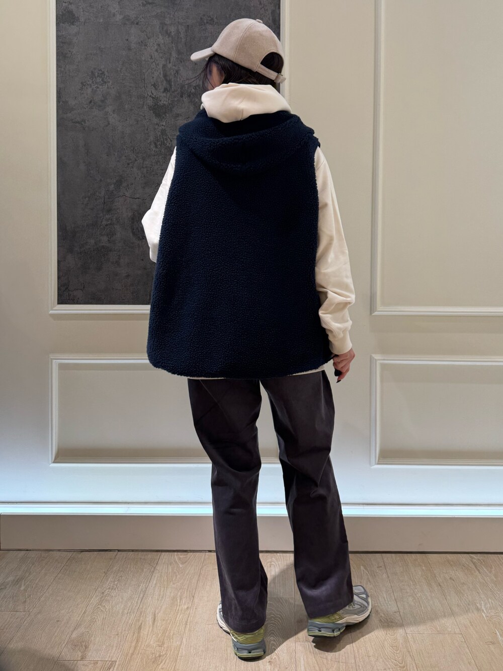 ホワイト系のパーカー、ブルー系のベスト、ブルー系のキャップを着用したレディースの秋コーディネートの4枚目の写真