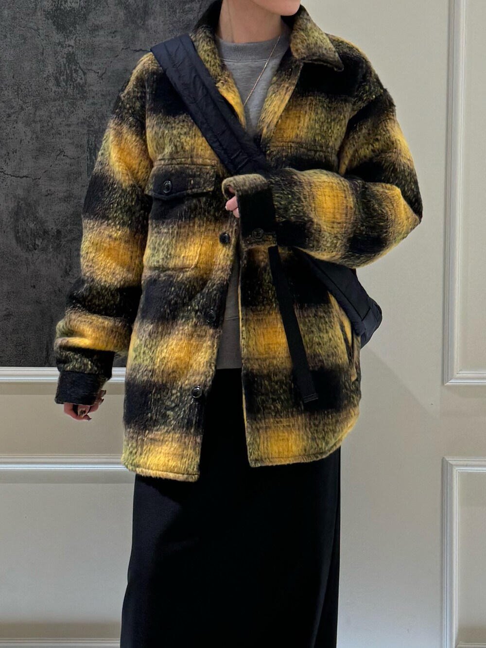 イエロー系のブルゾン、ブラック系のスカート、ブラック系のブーツを着用したレディースの冬コーディネートの2枚目の写真