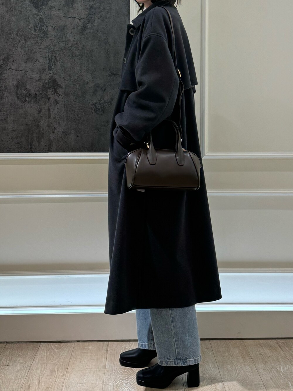 グレー系のステンカラーコート、ピンク系のニット/セーター、ブルー系のデニムパンツを着用したレディースの冬コーディネートの2枚目の写真