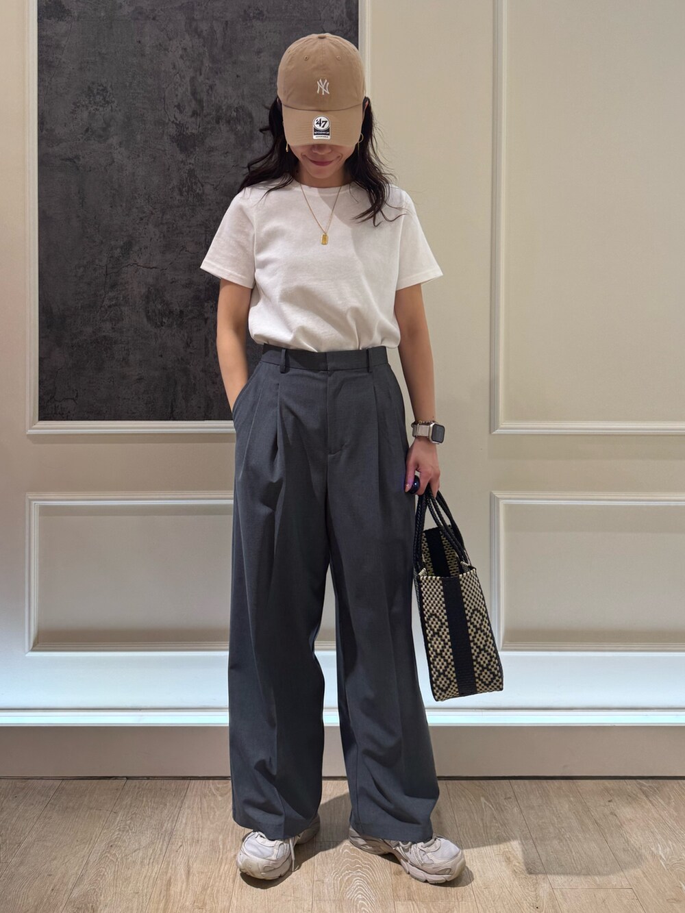 ホワイト系のTシャツ/カットソー、グレー系のスラックス、ブラック系のトートバッグを着用したレディースの夏コーディネートの2枚目の写真