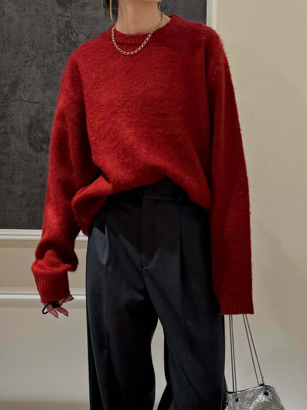 レッド系のニット/セーター、ホワイト系のスラックスを着用したレディースの冬コーディネートの2枚目の写真