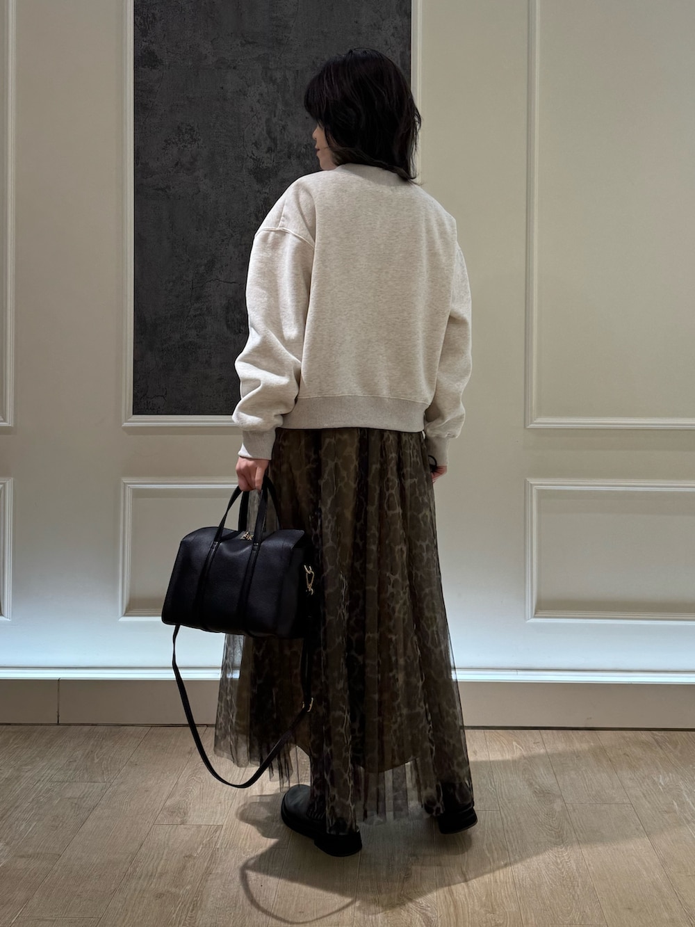 ホワイト系のスウェット、グレー系のスカート、ブラック系のショルダーバッグを着用したレディースの冬コーディネートの3枚目の写真