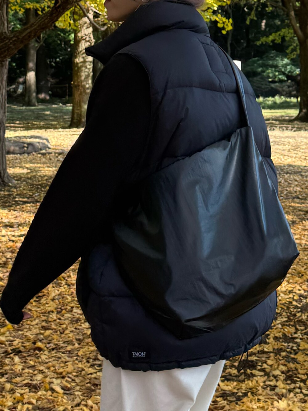 ブラック系のダウンベスト、ブラック系のニット/セーター、ホワイト系のその他パンツを着用したレディースの冬コーディネートの5枚目の写真