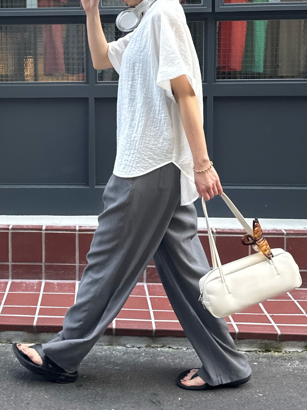 ホワイト系のシャツ/ブラウス、グレー系のサンダル、グレー系のスラックスを着用したレディースの夏コーディネートの3枚目の写真
