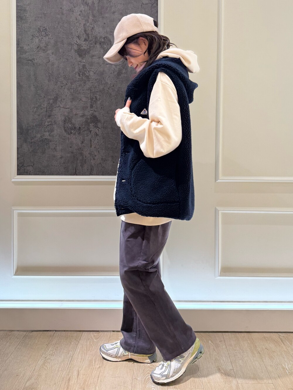 ホワイト系のパーカー、ブルー系のベスト、ブルー系のキャップを着用したレディースの秋コーディネートの3枚目の写真