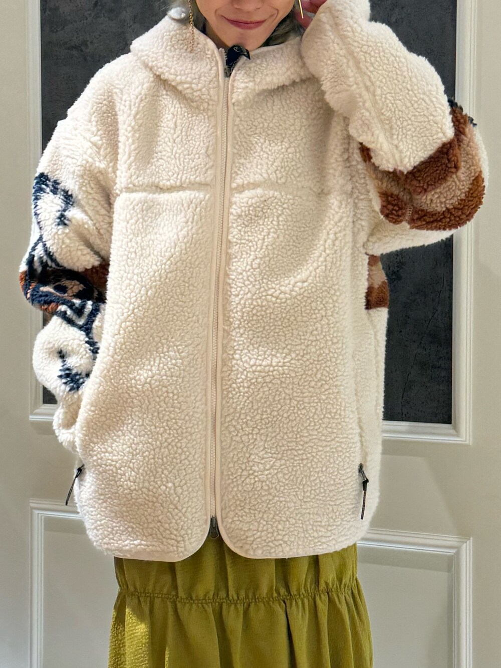 イエロー系のスカート、ホワイト系のブルゾンを着用したレディースの秋コーディネートの2枚目の写真