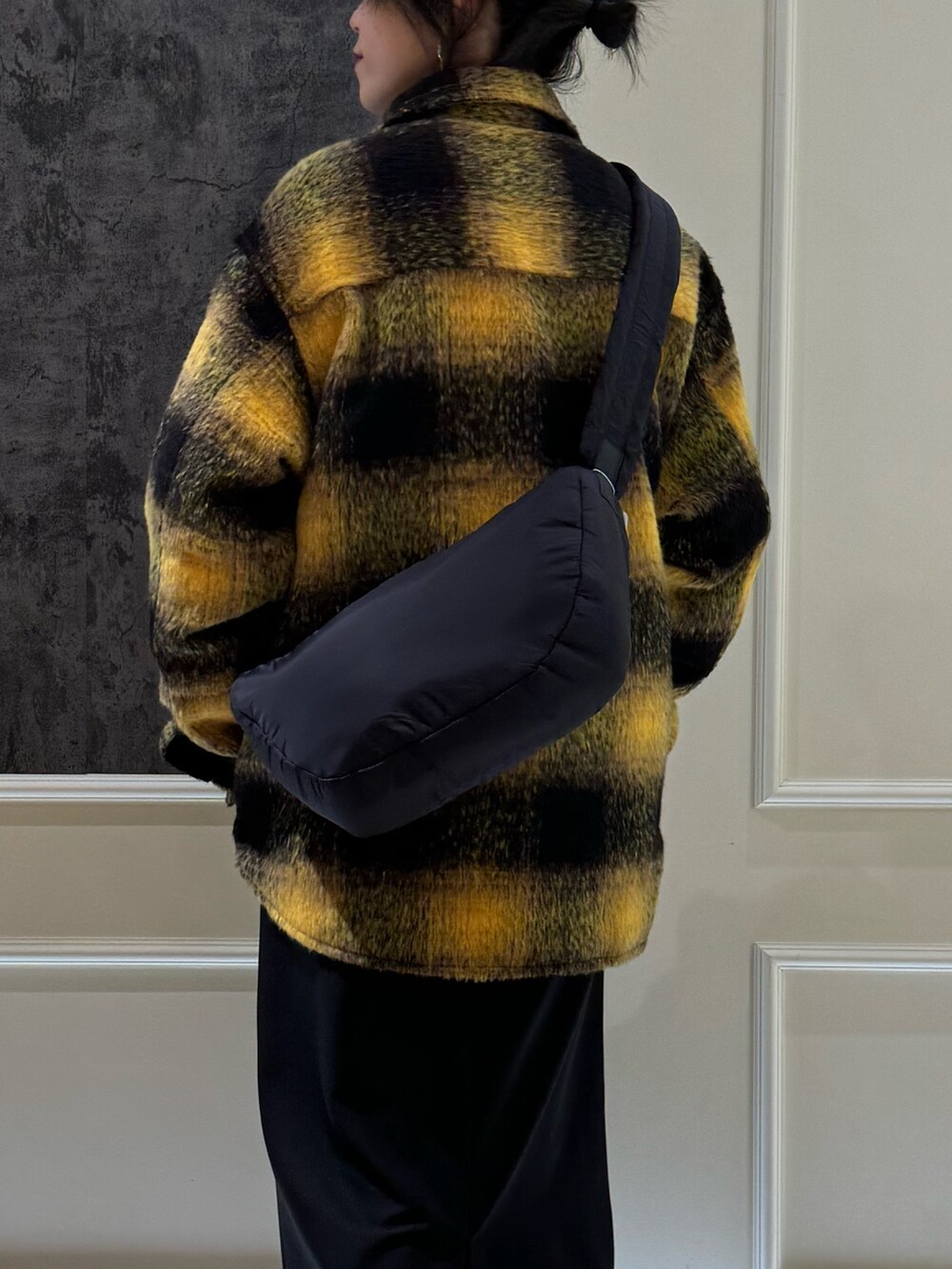 イエロー系のブルゾン、ブラック系のスカート、ブラック系のブーツを着用したレディースの冬コーディネートの3枚目の写真