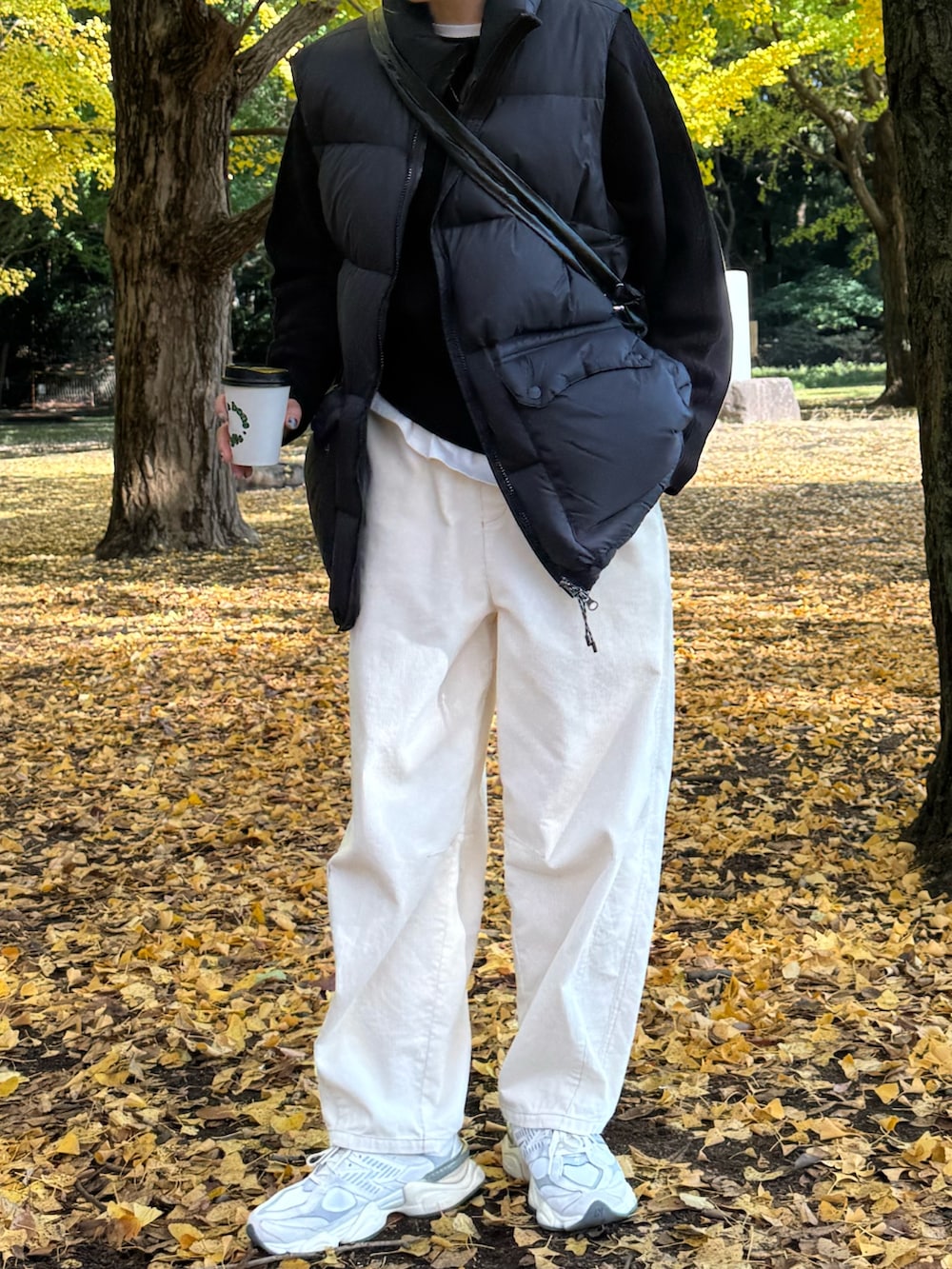 ブラック系のダウンベスト、ブラック系のニット/セーター、ホワイト系のその他パンツを着用したレディースの冬コーディネートの4枚目の写真