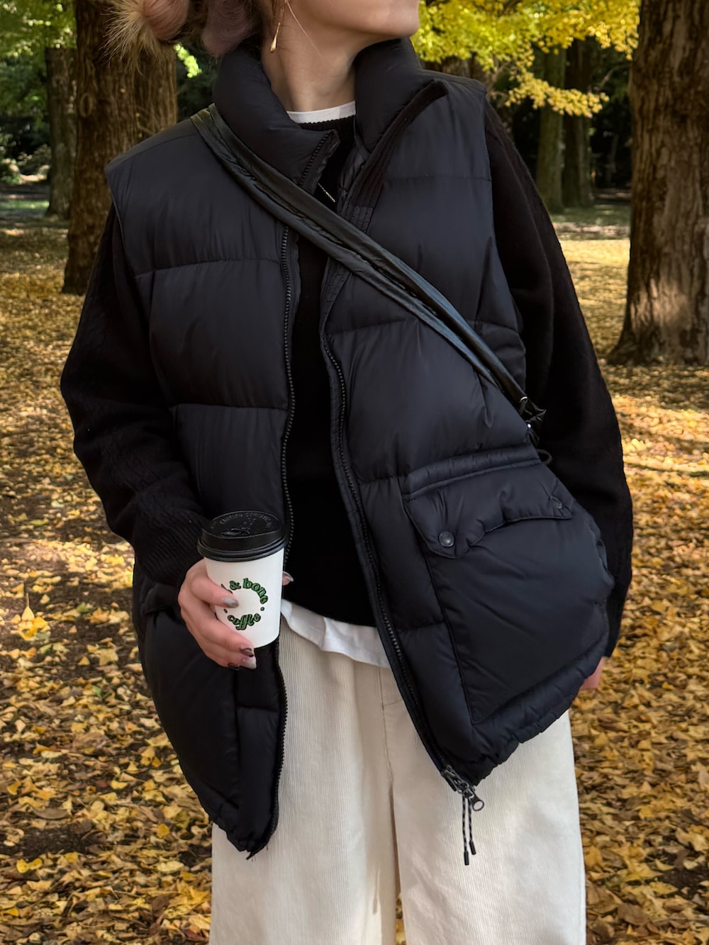 ブラック系のダウンベスト、ブラック系のニット/セーター、ホワイト系のその他パンツを着用したレディースの冬コーディネートの2枚目の写真