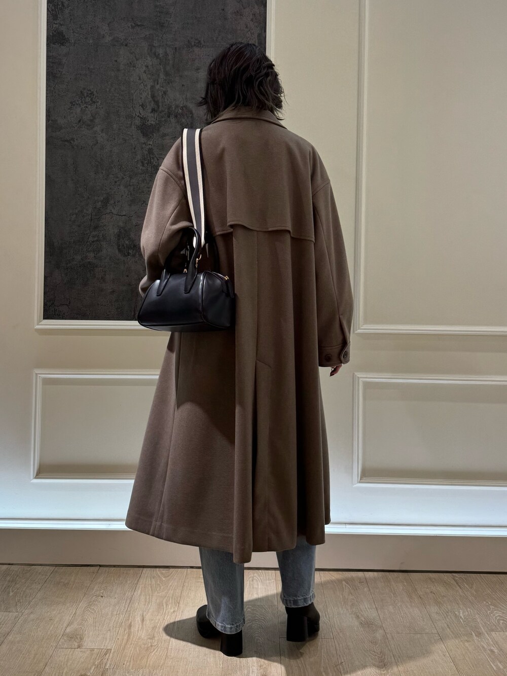 ブルー系のデニムパンツ、ブラック系のブーツ、ブラウン系のステンカラーコートを着用したレディースの冬コーディネートの3枚目の写真