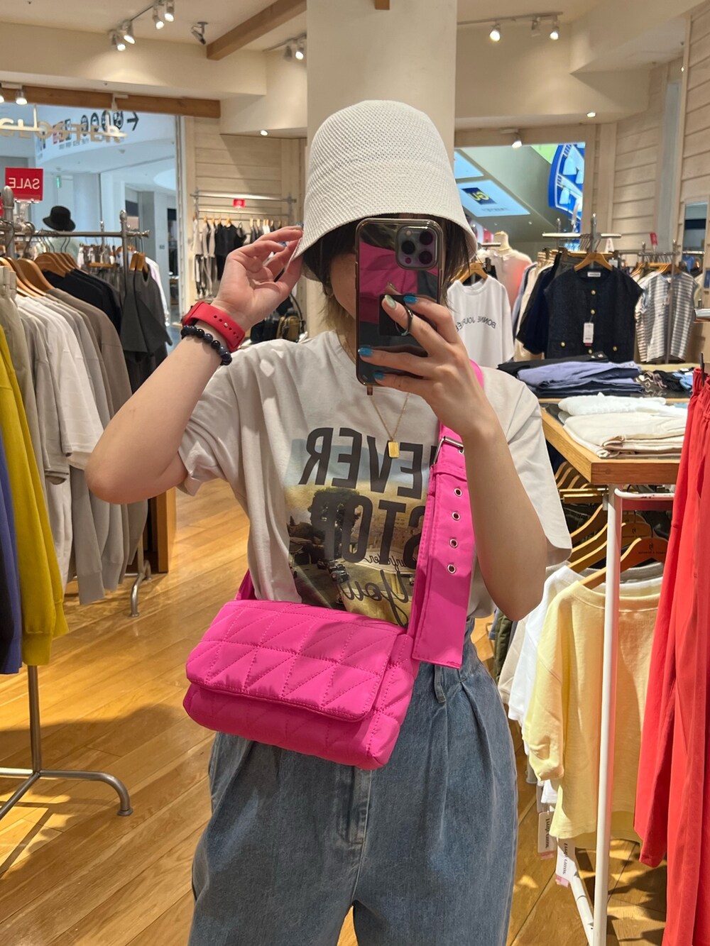 ブルー系のデニムパンツ、ピンク系のショルダーバッグ、ホワイト系のハットを着用したレディースの夏コーディネートの2枚目の写真