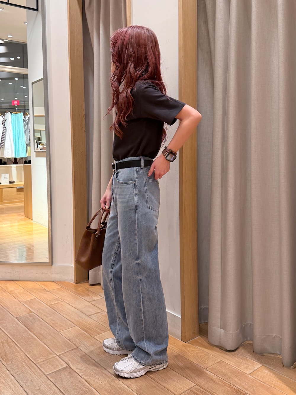 グレー系のポロシャツ、ブルー系のデニムパンツ、ブラウン系のトートバッグを着用したレディースの春コーディネートの2枚目の写真