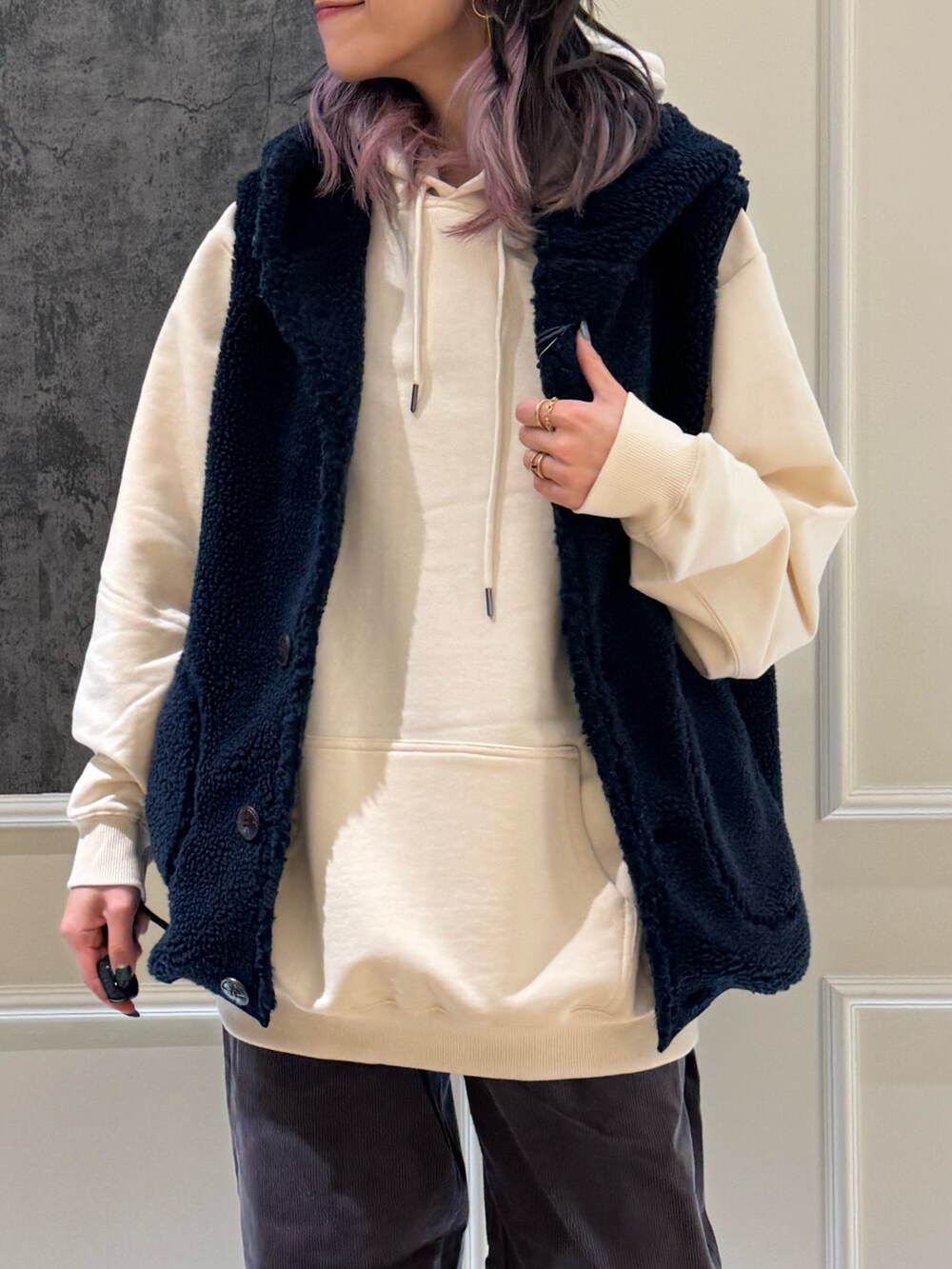 ホワイト系のパーカー、ブルー系のベスト、ブルー系のキャップを着用したレディースの秋コーディネートの2枚目の写真