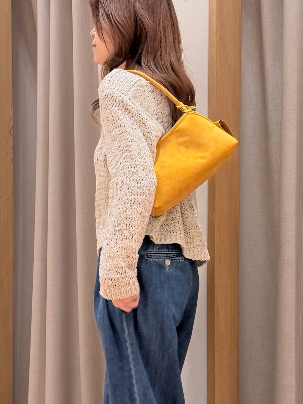 ピンク系のニット/セーター、ブルー系のデニムパンツ、イエロー系のショルダーバッグを着用したレディースの春コーディネートの3枚目の写真