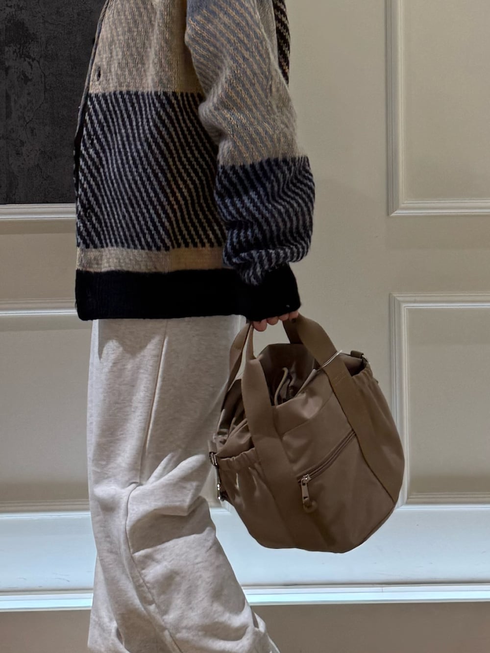 グレー系のカーディガン/ボレロ、グレー系のスウェットパンツ、ベージュ系のショルダーバッグを着用したレディースの秋コーディネートの2枚目の写真