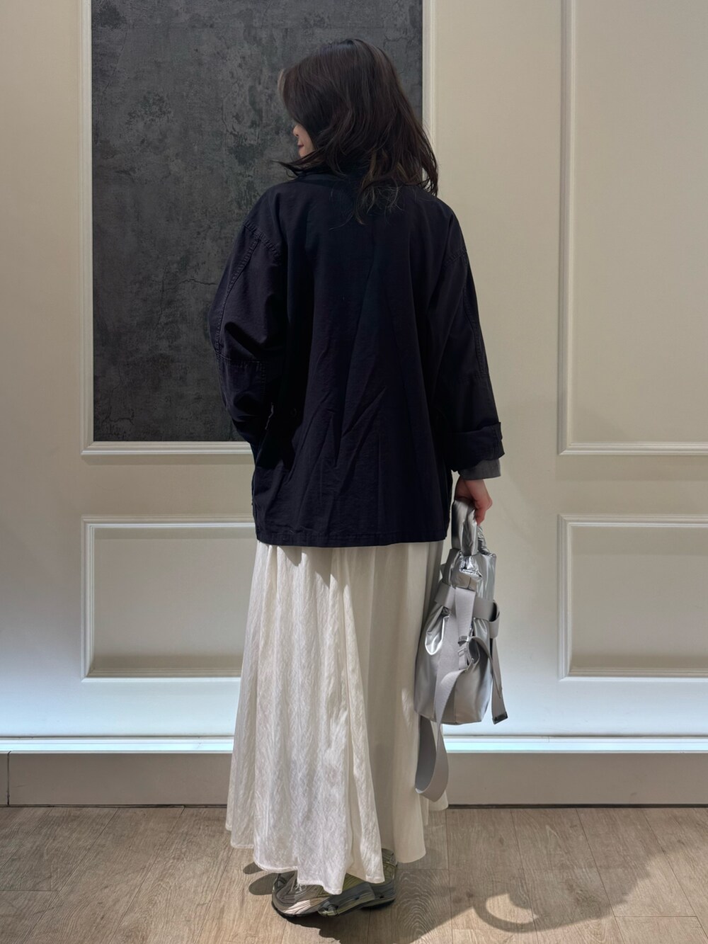 ブラック系のミリタリージャケット、ホワイト系のスカート、シルバー系のショルダーバッグを着用したレディースの春コーディネートの3枚目の写真