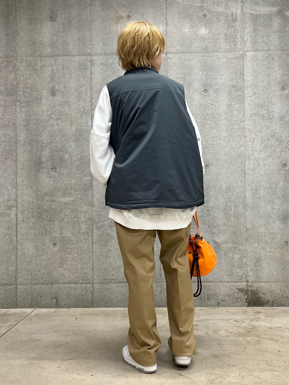 グレー系のベスト、ベージュ系のその他パンツ、オレンジ系のショルダーバッグを着用したレディースの春コーディネートの3枚目の写真