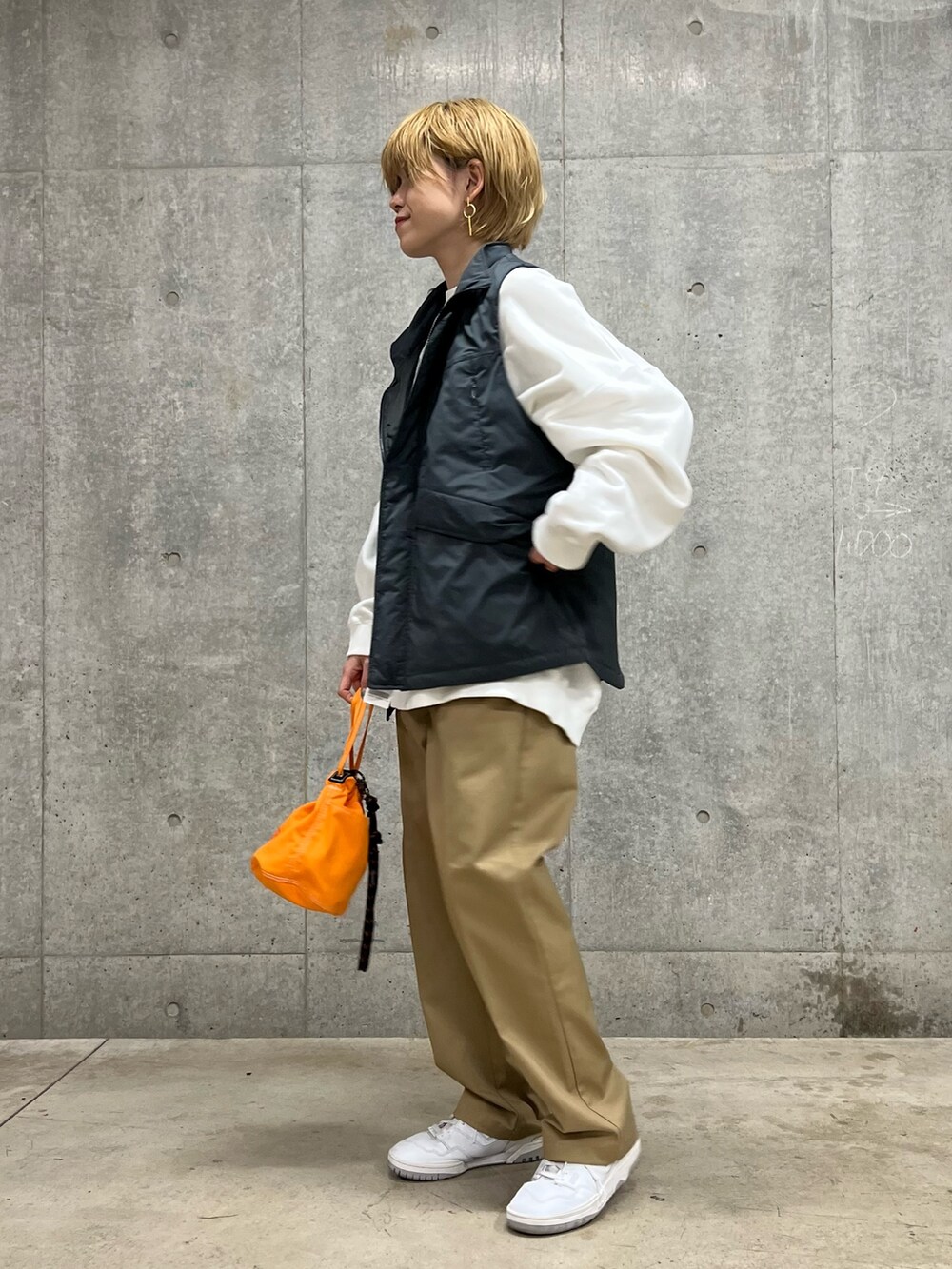 グレー系のベスト、ベージュ系のその他パンツ、オレンジ系のショルダーバッグを着用したレディースの春コーディネートの2枚目の写真