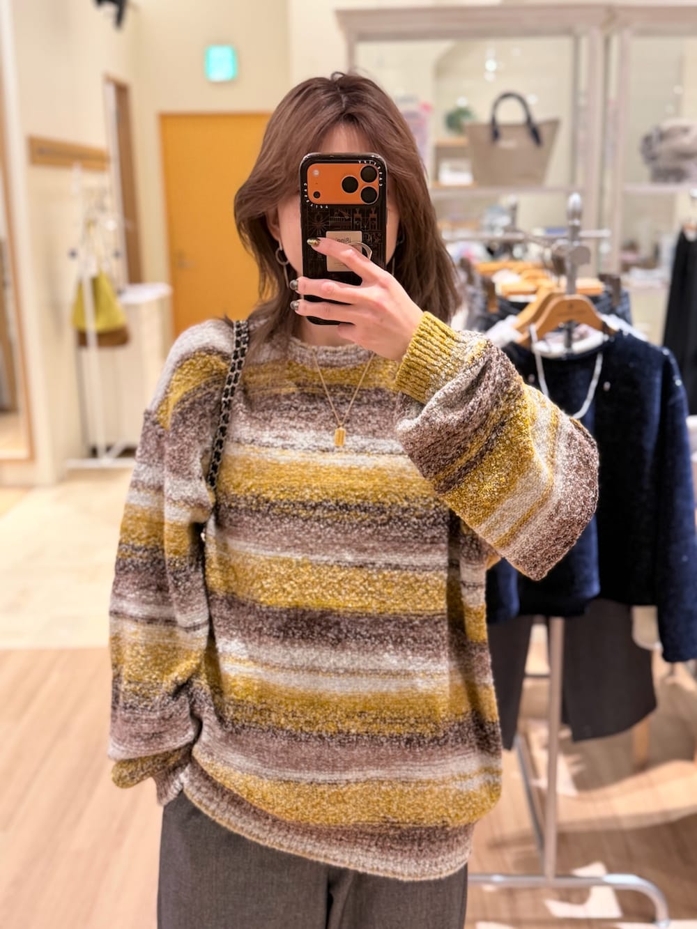 イエロー系のニット/セーター、グレー系のその他パンツ、ブラック系のショルダーバッグを着用したレディースの冬コーディネートの3枚目の写真