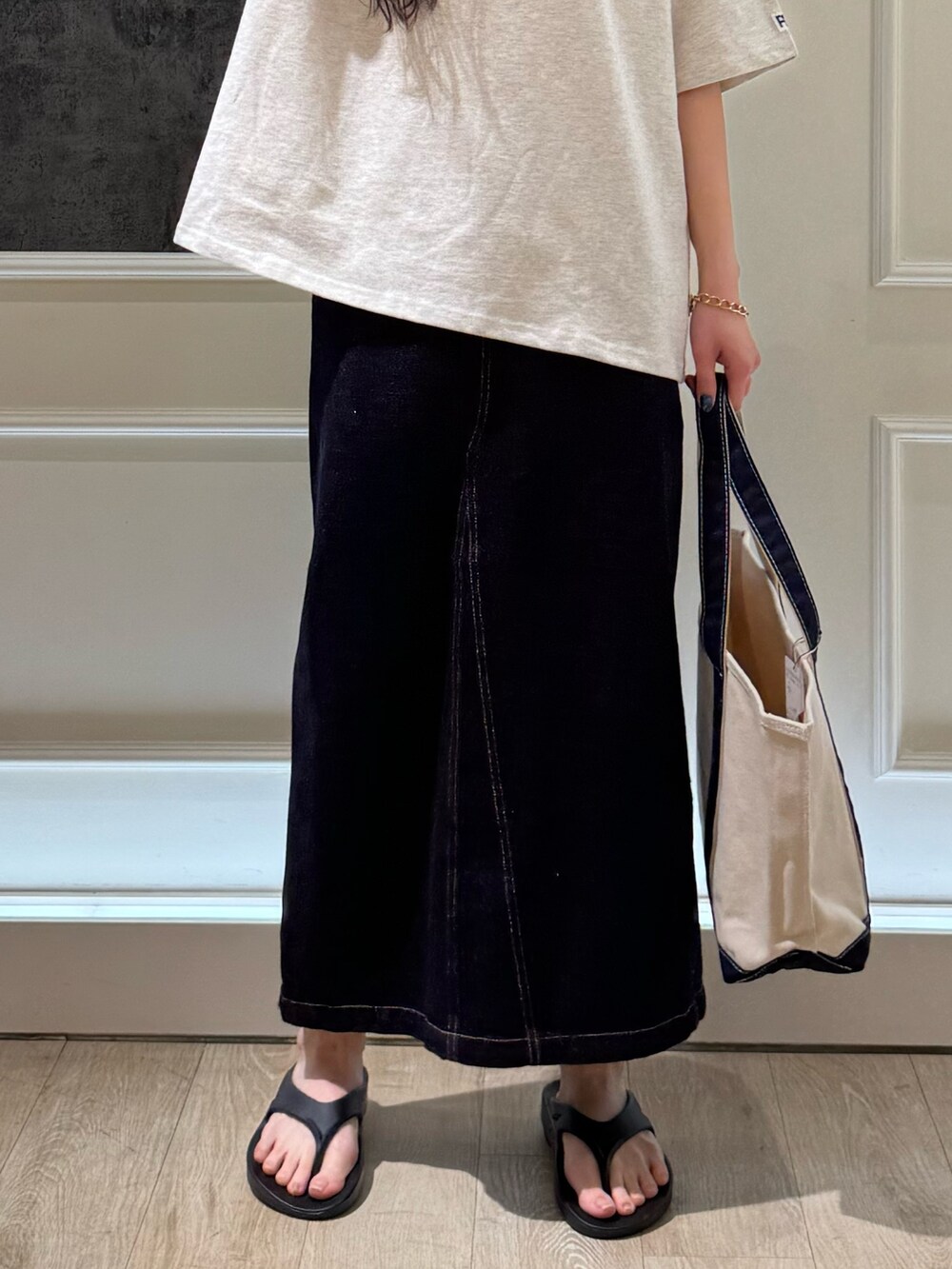 ベージュ系のTシャツ/カットソー、ブルー系のデニムスカート、ブラック系のトートバッグを着用したレディースの春コーディネートの4枚目の写真