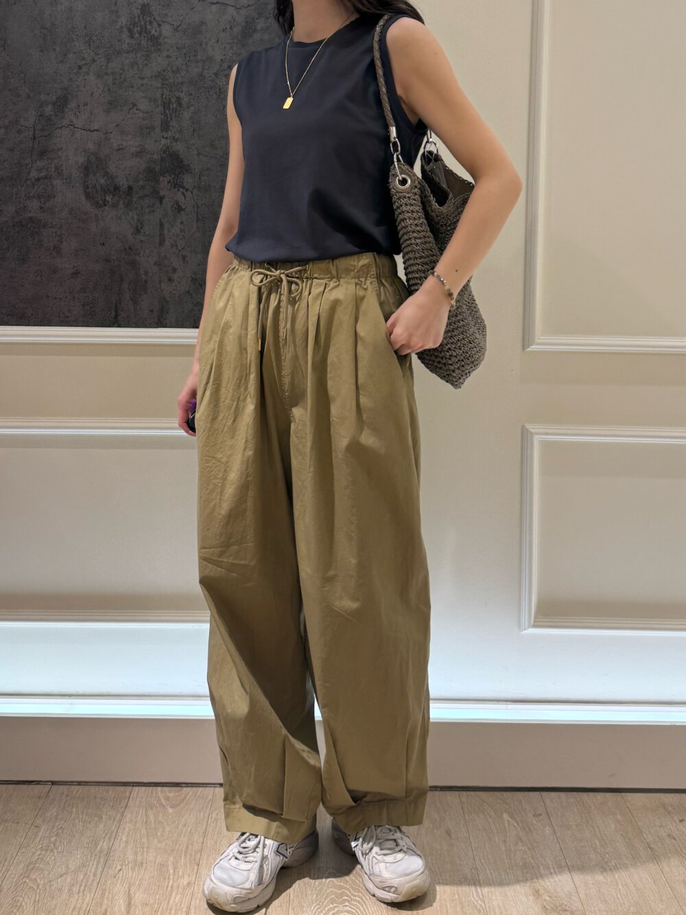 グレー系のタンクトップ、ベージュ系のその他パンツ、ホワイト系のキャップを着用したレディースの夏コーディネートの2枚目の写真