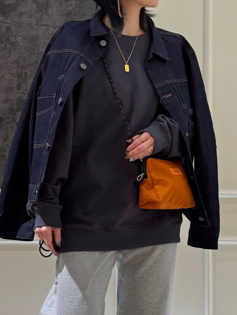 ブルー系のデニムジャケット、グレー系のスウェット、オレンジ系のショルダーバッグを着用したレディースの春コーディネートの2枚目の写真