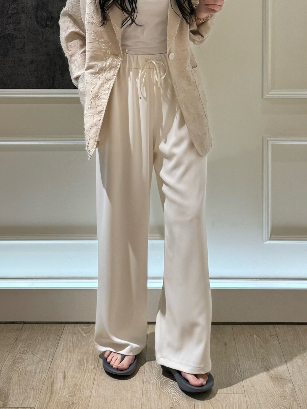 ベージュ系のテーラードジャケット、ブラック系のサンダル、ホワイト系のその他パンツを着用したレディースの春コーディネートの3枚目の写真