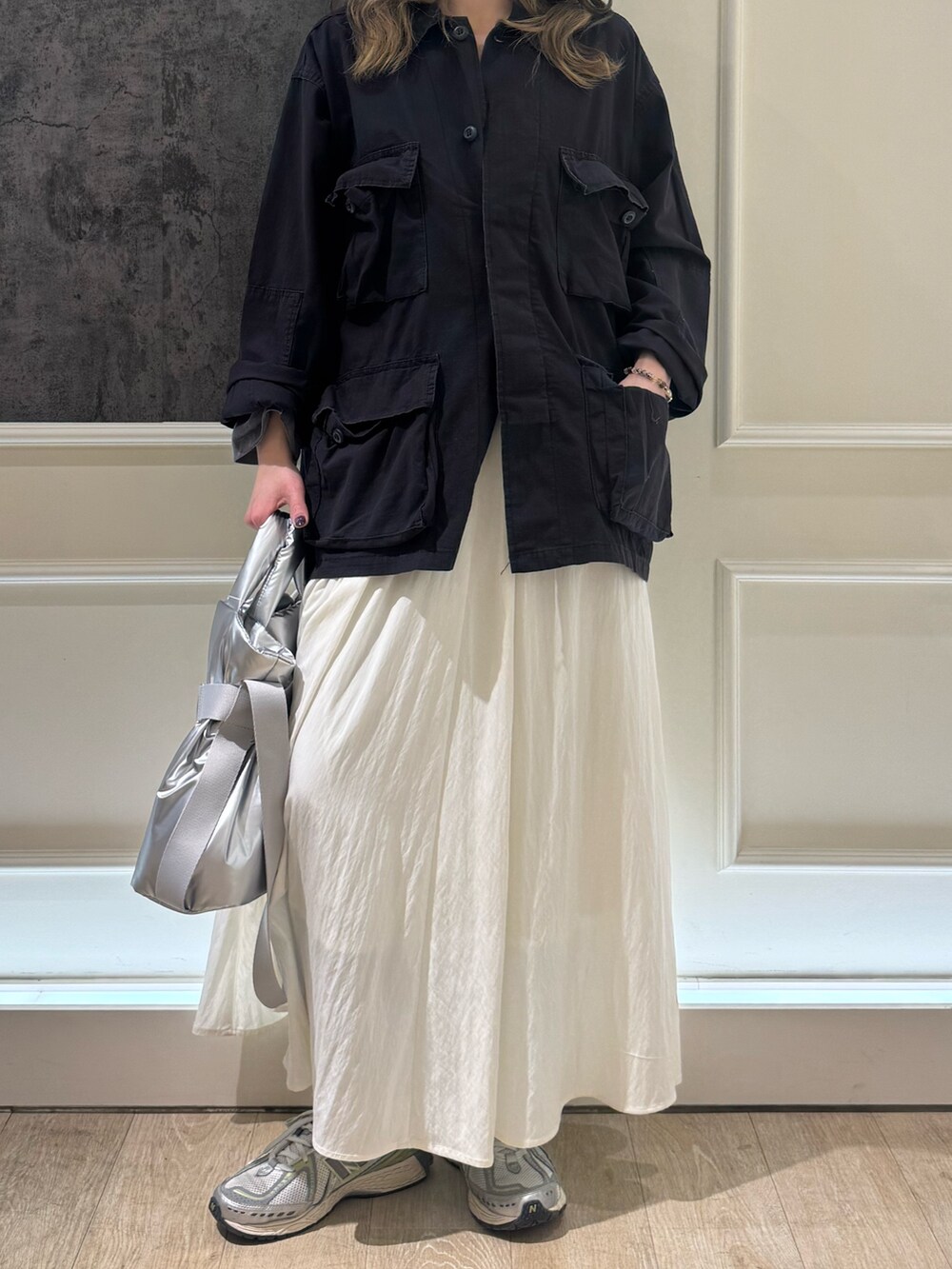 ブラック系のミリタリージャケット、ホワイト系のスカート、シルバー系のショルダーバッグを着用したレディースの春コーディネートの4枚目の写真