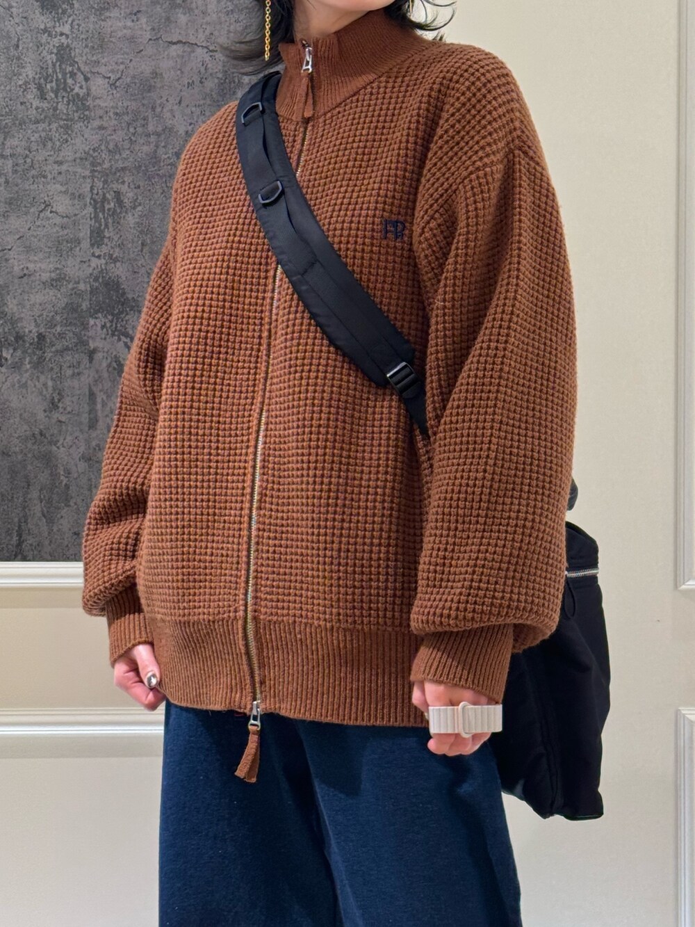 イエロー系のニット/セーター、ブルー系のデニムパンツ、ブラック系のショルダーバッグを着用したレディースの冬コーディネートの2枚目の写真