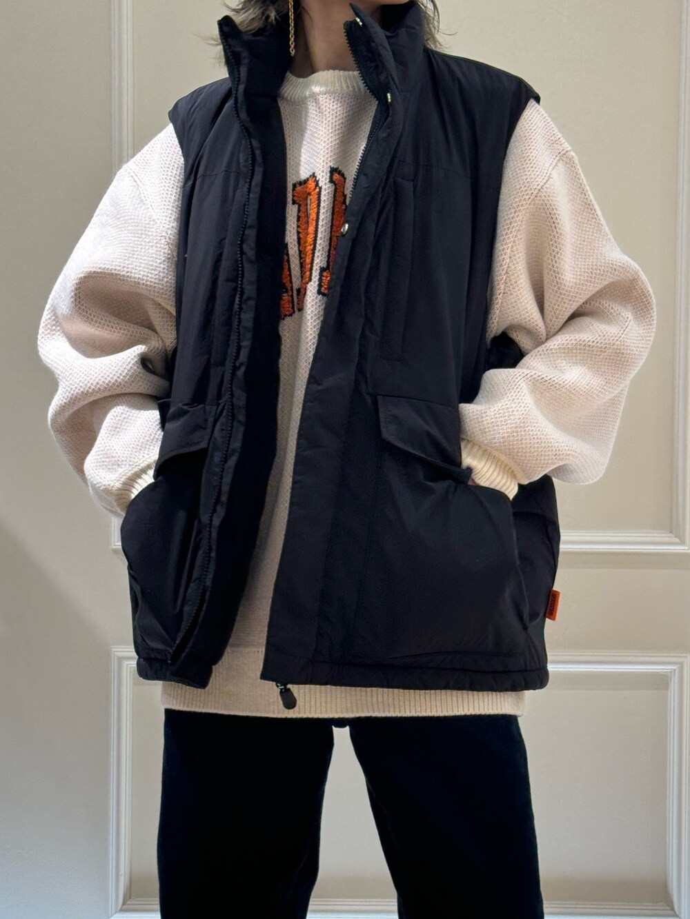 ブラック系のベスト、ホワイト系のニット/セーター、ベージュ系のハットを着用したレディースの秋コーディネートの3枚目の写真