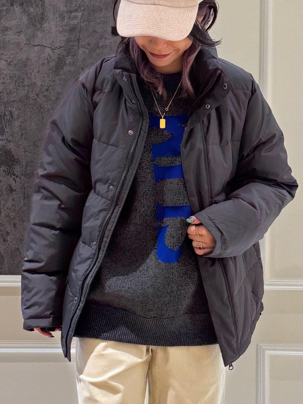 グレー系のダウンジャケット/コート、グレー系のニット/セーター、ブルー系のキャップを着用したレディースの秋コーディネートの2枚目の写真