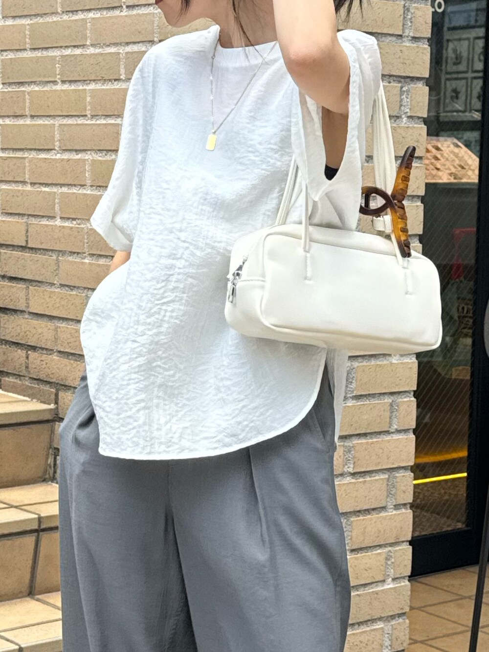 ホワイト系のシャツ/ブラウス、グレー系のサンダル、グレー系のスラックスを着用したレディースの夏コーディネートの5枚目の写真