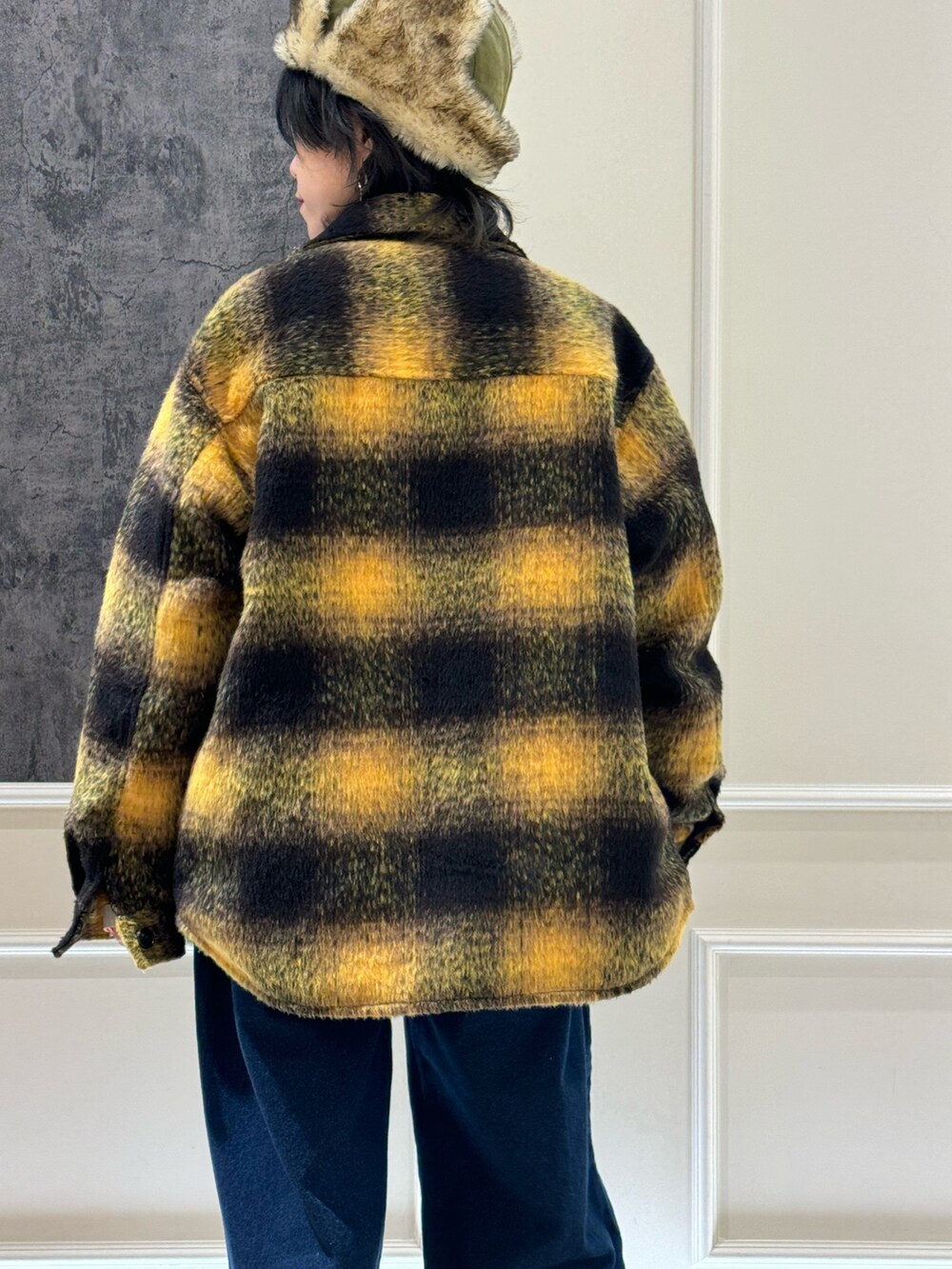 イエロー系のブルゾン、ブラック系のスウェット、ブルー系のデニムパンツを着用したレディースの冬コーディネートの3枚目の写真