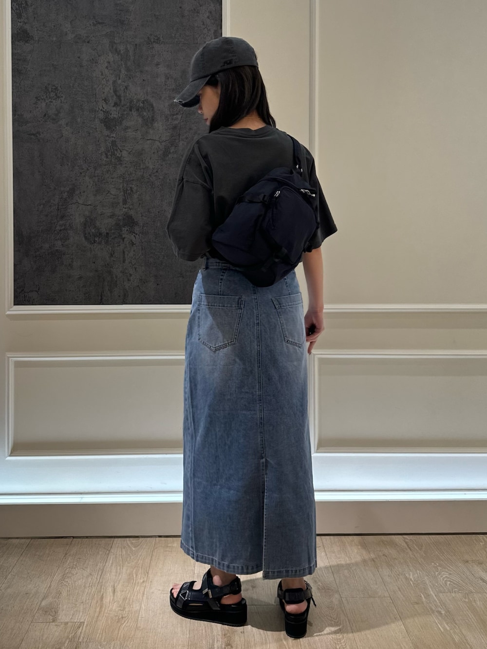 ブラック系のTシャツ/カットソー、ブルー系のデニムスカート、ブラック系のショルダーバッグを着用したレディースの春コーディネートの4枚目の写真