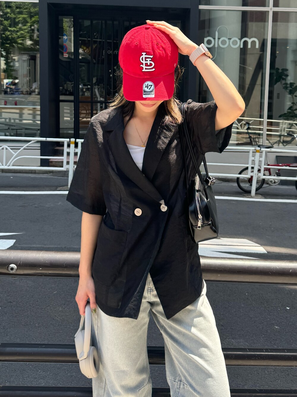 ブラック系のダウンジャケット/コート、ブルー系のデニムパンツ、ホワイト系のボストンバッグを着用したレディースの夏コーディネートの4枚目の写真