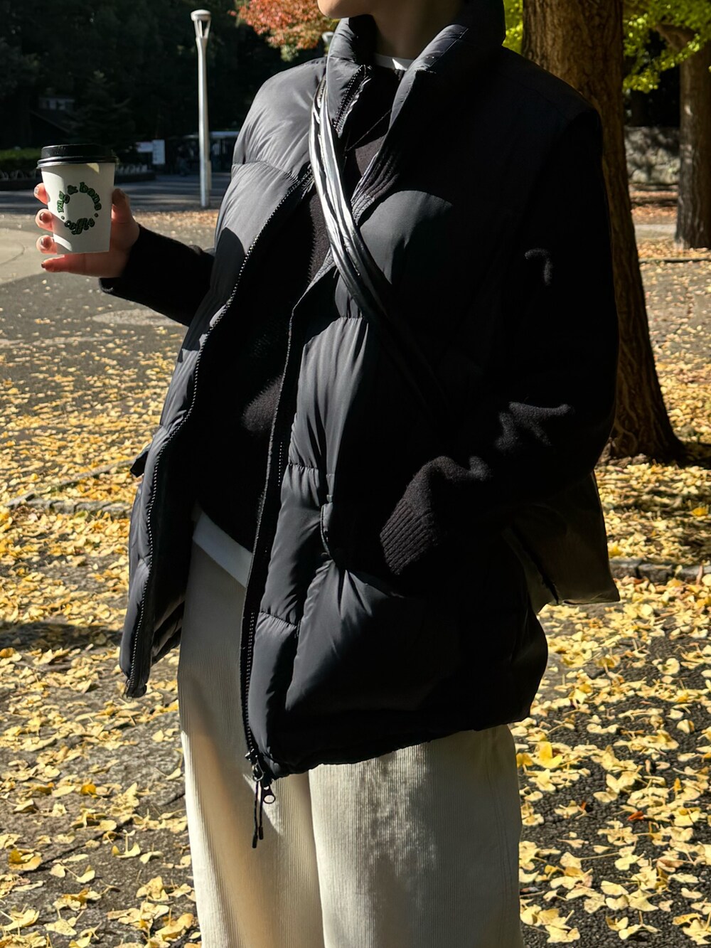 ブラック系のダウンベスト、ブラック系のニット/セーター、ホワイト系のその他パンツを着用したレディースの冬コーディネートの6枚目の写真