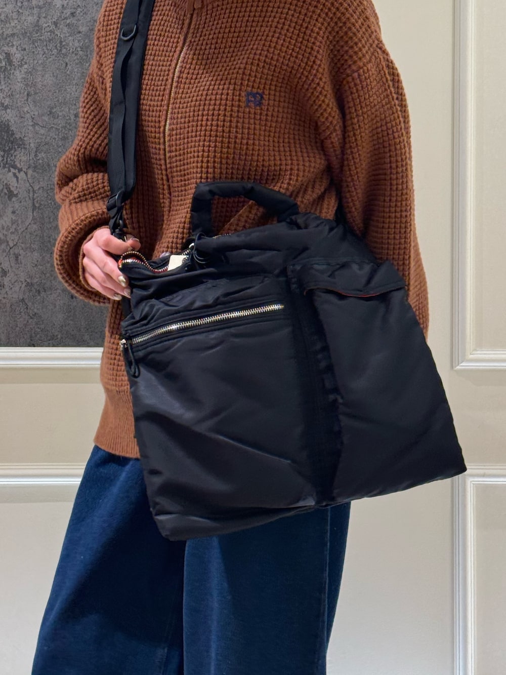 イエロー系のニット/セーター、ブルー系のデニムパンツ、ブラック系のショルダーバッグを着用したレディースの冬コーディネートの4枚目の写真