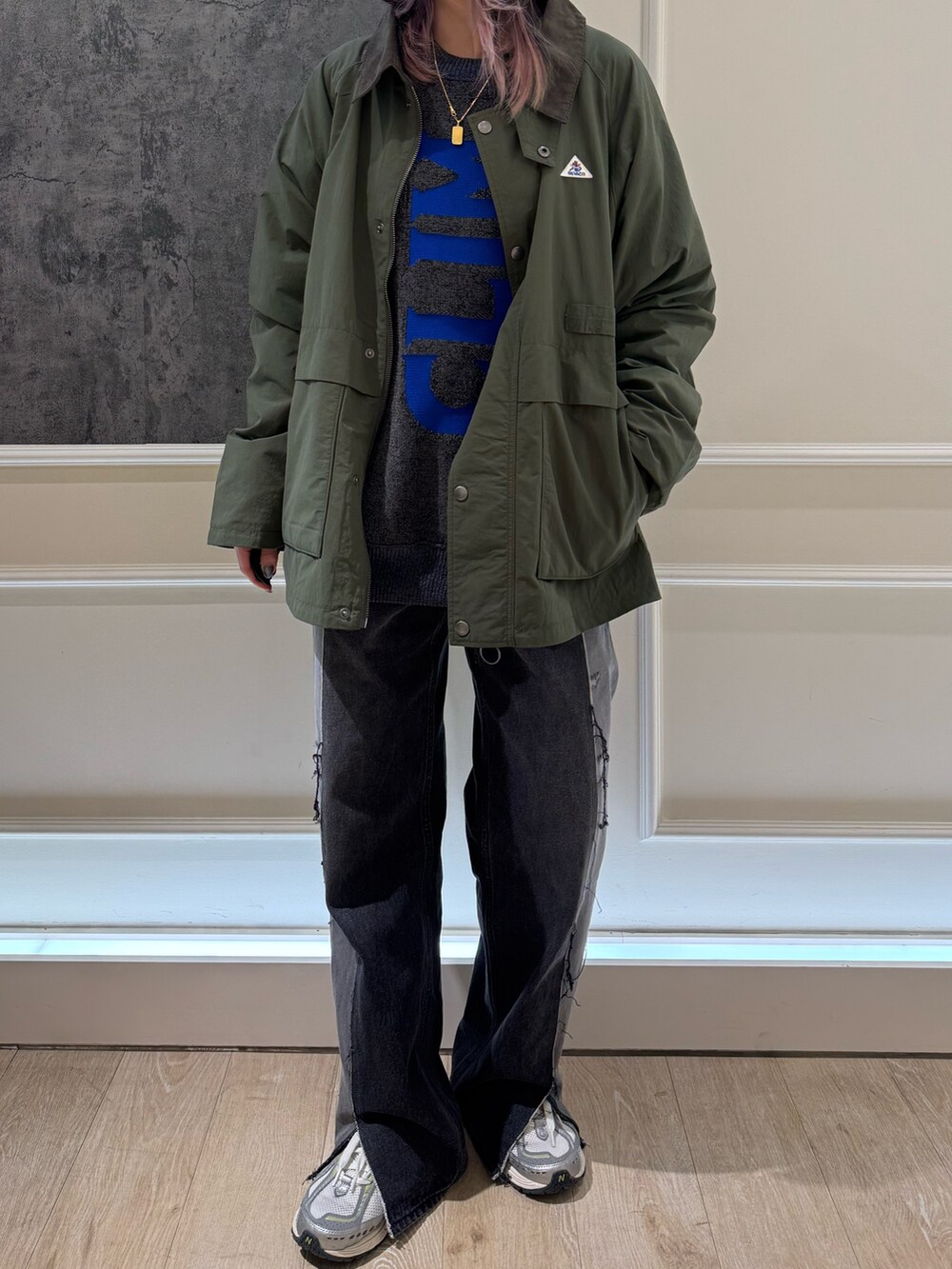 グリーン系のブルゾン、グレー系のニット/セーター、ブルー系のキャップを着用したレディースの秋コーディネートの2枚目の写真