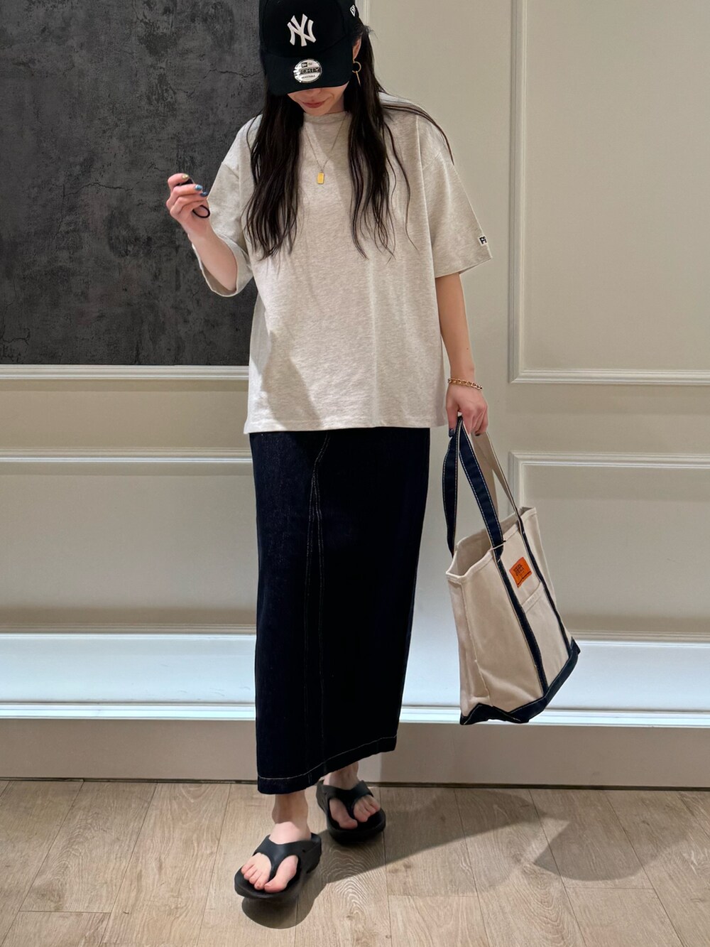 ベージュ系のTシャツ/カットソー、ブルー系のデニムスカート、ブラック系のトートバッグを着用したレディースの春コーディネートの2枚目の写真
