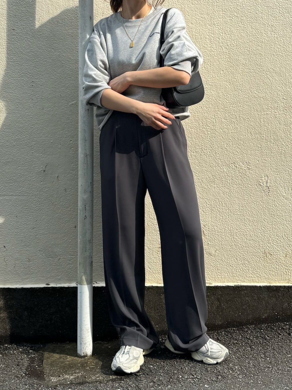 グレー系のスウェット、グレー系のスラックス、ブラック系のショルダーバッグを着用したレディースの春コーディネートの3枚目の写真
