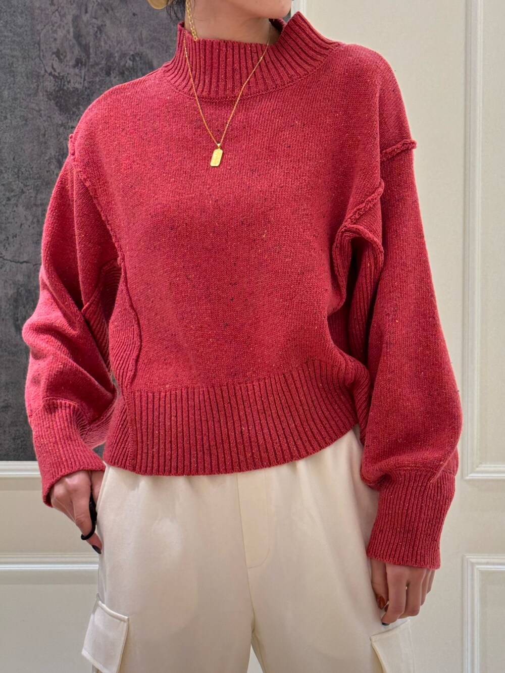 ピンク系のニット/セーター、ホワイト系のカーゴパンツ、ブラック系のブーツを着用したレディースの冬コーディネートの2枚目の写真