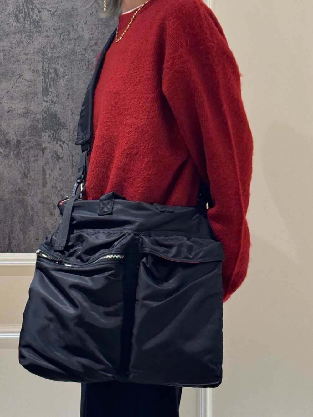 レッド系のニット/セーター、ブラック系のショルダーバッグ、ブラック系のスラックスを着用したレディースの冬コーディネートの2枚目の写真