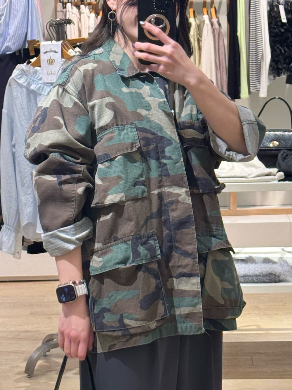 ブラウン系のミリタリージャケット、グレー系のスラックス、ブラック系のショルダーバッグを着用したレディースの春コーディネートの2枚目の写真