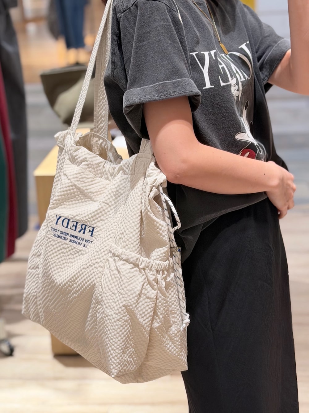グレー系のTシャツ/カットソー、ブラック系のスカート、ホワイト系のトートバッグを着用したレディースの夏コーディネートの3枚目の写真