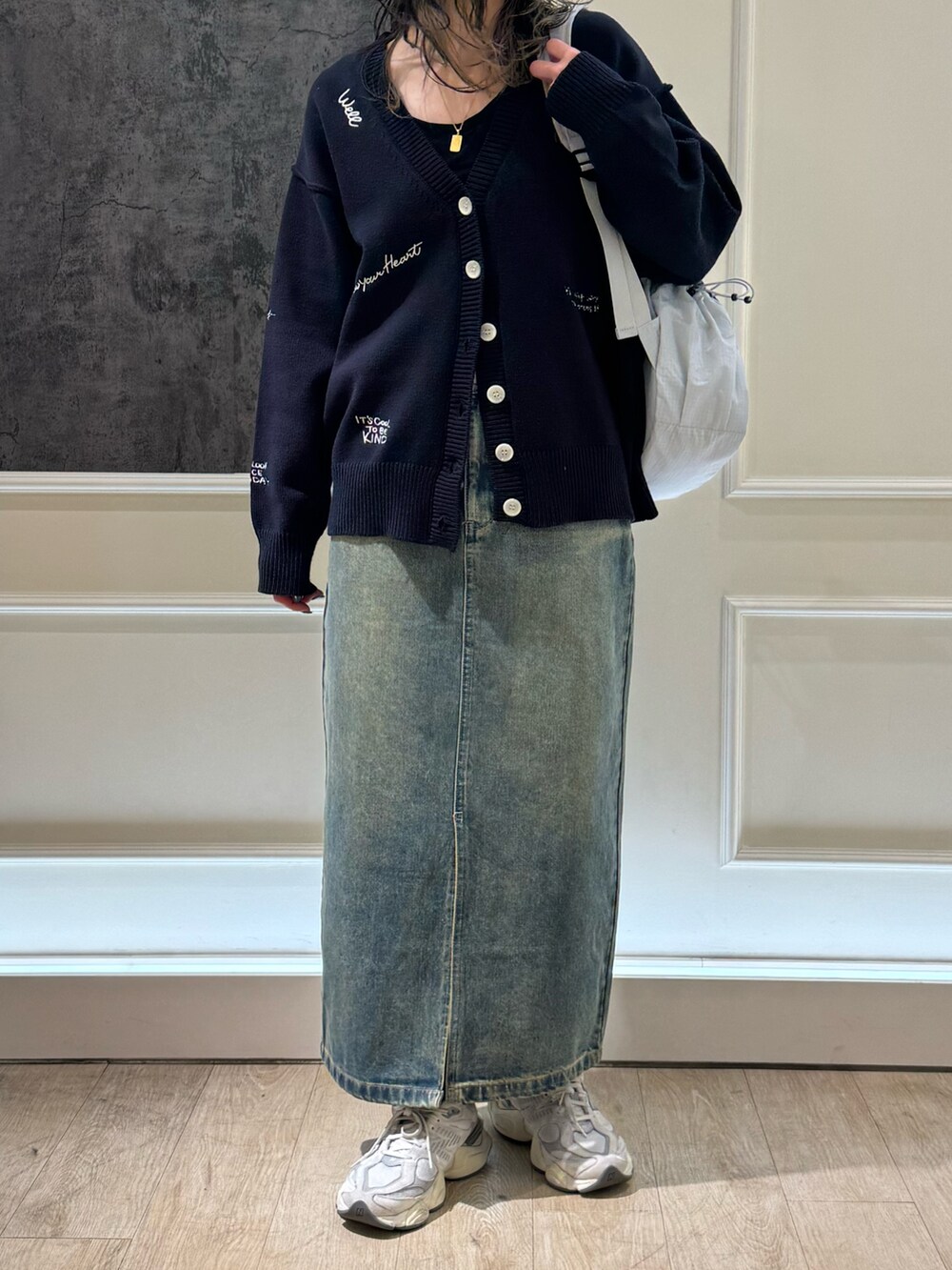 ホワイト系のカーディガン/ボレロ、ブルー系のデニムスカート、ブラック系のバックパック/リュックを着用したレディースの冬コーディネートの2枚目の写真