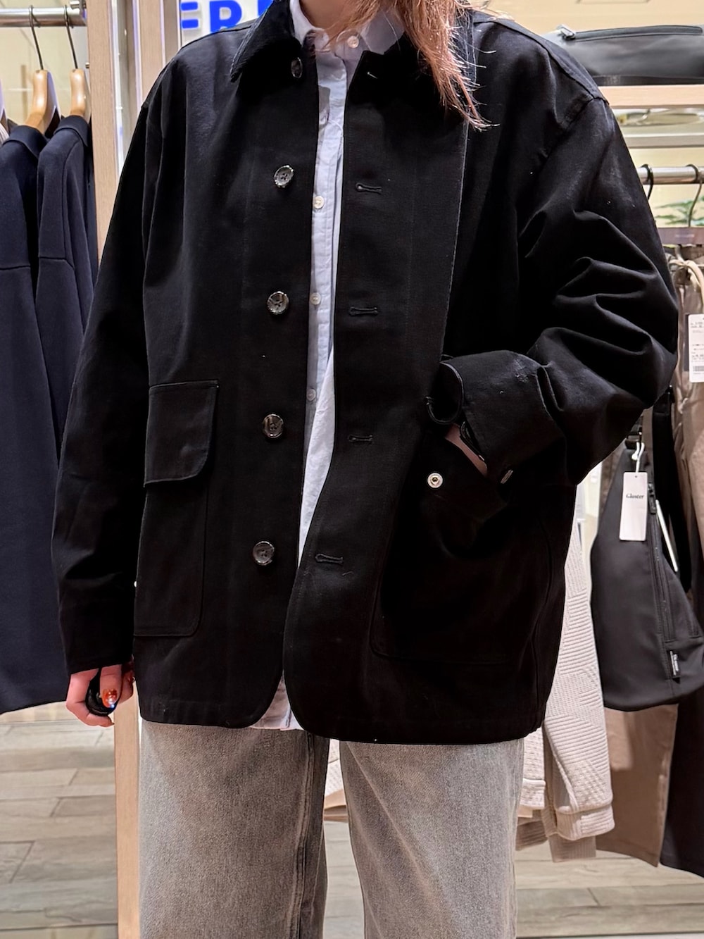 ブラック系のブルゾン、ブルー系のシャツ/ブラウス、ブルー系のデニムパンツを着用したレディースの春コーディネートの2枚目の写真