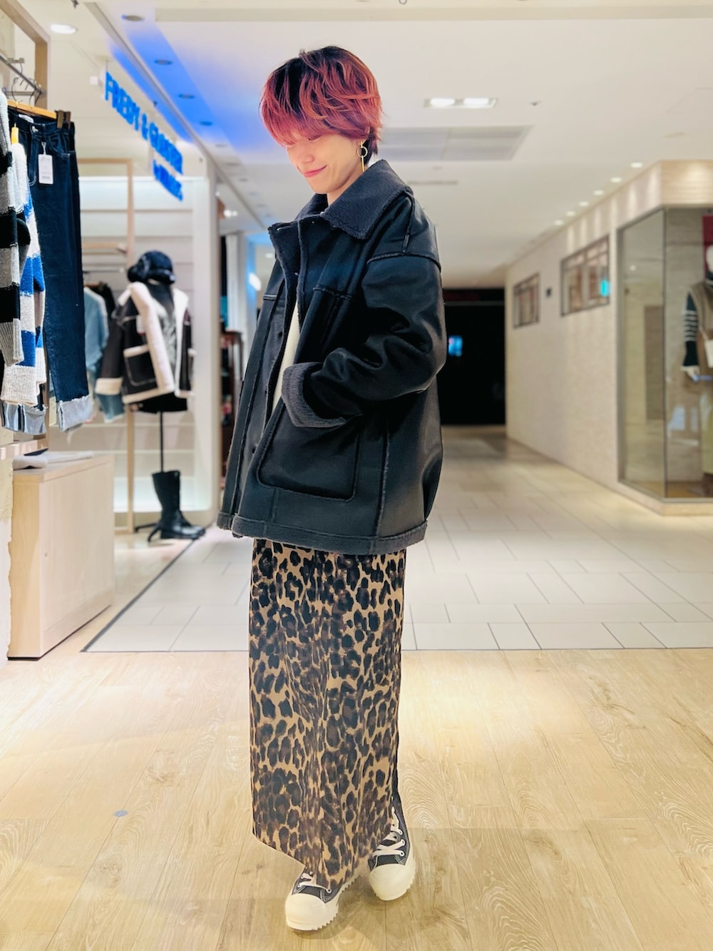 ブラック系のムートンコート、ベージュ系のスカート、ブラック系のスニーカーを着用したレディースの冬コーディネートの2枚目の写真