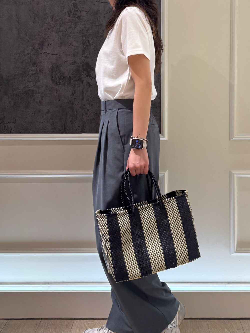 ホワイト系のTシャツ/カットソー、グレー系のスラックス、ブラック系のトートバッグを着用したレディースの夏コーディネートの3枚目の写真